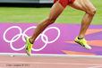 A cropped generic image of the legs of a runner racinbg past the Olympic rings on the track at the London 2012 Olympic Games.