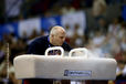 A portrait image of British National Coach Andrei Popov preparing the pommel horse before his gymnast competes.