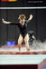 Niamh Rippin (Great Britain) lands in a cloud of chalk after competing on asymmetric bars at the 2012 FIG World Cup in the Emirates Arena