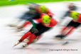 A slow motion blurred action image from the short track speed skating event.