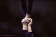 A generic close up image of the hands of two female sports acrobats in a supported handstand balance during competition.